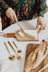 Kaboompics - Woman is cutting bread on cutting board