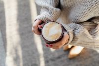 Kaboompics - Woman Holding a Foamy Latte in a Brown Ceramic Cup, Cozy Coffee Break with Knit Sweater