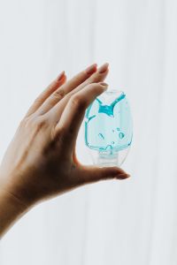 Kaboompics - Hand Reaching for Blue Sanitizer Bottle in Natural Light