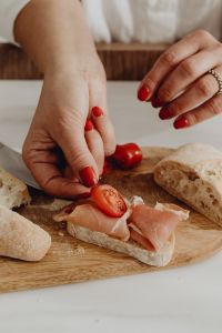 Kaboompics - Hands Preparing Cherry Tomato and Prosciutto Bruschetta