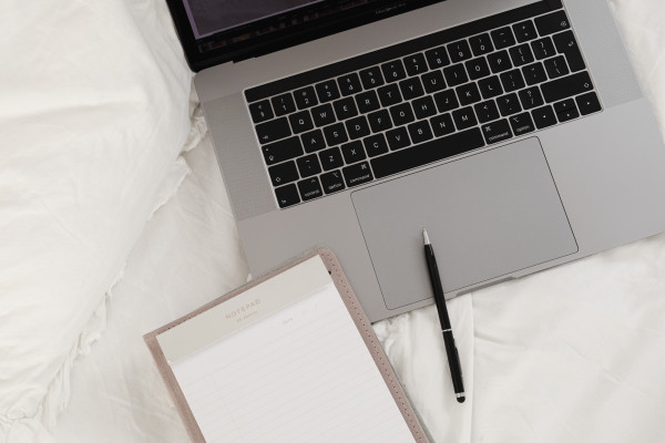 Working with a laptop in bed - white cotton bedding - blank notebook ...