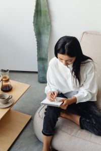 Kaboompics - Woman Journaling Beside a Chemex and Small Table