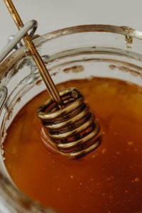 Kaboompics - Close-Up of Honey Dipper Resting in Amber Honey, Glass Jar Macro