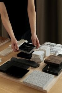 Kaboompics - Designer Holding Black Marble Sample over Stone and Wood Material Board