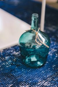 Kaboompics - Turquoise Glass Bottle with Twine on a Patterned Blue Rug