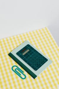Kaboompics - Green Calculator and Paper Clip With Copy Space on Yellow Gingham