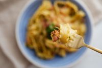 Kaboompics - Forkful of Carbonara with Blurred Blue Bowl Background