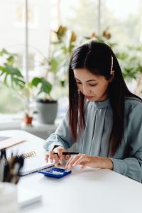 Kaboompics - Asian Woman Using a Calculator While Writing Notes at Her Desk