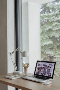 Kaboompics - Bright Home Office Desk with Laptop and White Lamp in Front of a Tree-Lined Window