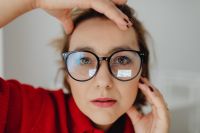 Kaboompics - Close-Up Portrait of Woman Touching Temple and Eyeglasses at Her Desk