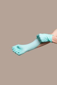 Kaboompics - Turquoise Medical Glove Cuff Being Adjusted, Vertical Healthcare Safety Background with Copy Space