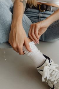 Kaboompics - Close-Up Hands Adjusting Ribbed White Socks beneath Light Blue Jeans, Fashion Detail