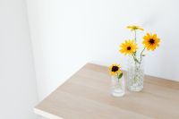 Kaboompics - Yellow Flowers in Clear Vases With Copy Space on a Light Table