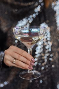 Kaboompics - Close-Up Champagne Coupe and Ringed Hand Framed by Silver Party Bokeh