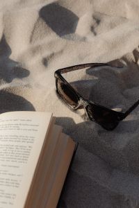 Kaboompics - Close-Up of Book Pages and Sunglasses on Textured Sand