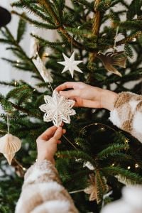 Kaboompics - Hands Holding White Paper Snowflake Ornament on Christmas Tree