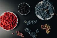 Kaboompics - Berry Bowls and Grape Clusters on a Black Table