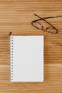 Kaboompics - Tortoiseshell Eyeglasses and Spiral Notebook on Oak Desk, Vertical Writing Copy Space