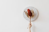 Kaboompics - Dried Flower Stem Held Over Marble with Open Space for Natural Brand Mockups