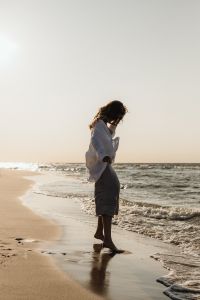 Kaboompics - Woman Walking Along Waterline in White Shirt and Satin Skirt