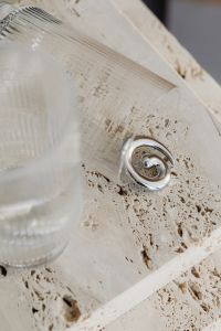 Kaboompics - Silver Spiral Earring Beside Ribbed Glassware