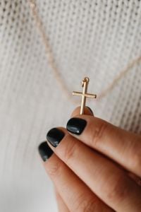 Kaboompics - Close-Up of Fingers Holding a Gold Cross Pendant
