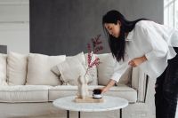 Kaboompics - Woman Arranging a Vase and Candle in the Living Room