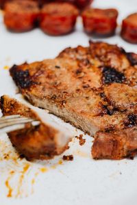 Kaboompics - Close-Up Grilled Pork Neck with Soft-Focus Sausage Medallions in Background