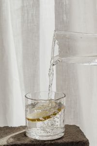 Kaboompics - Lemon Water Pouring Into a Textured Glass