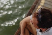 Kaboompics - Overhead Man Seated Beside Water on Old Wooden Pier, Sunglasses Pushed Up