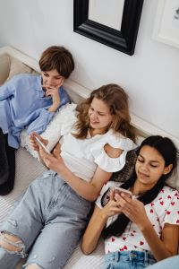 Kaboompics - Three Teenagers Using Smartphones Together in a Bright Bedroom Lifestyle Photo