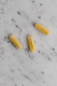 Kaboompics - Golden Softgel and Bead-Filled Capsules on Marble
