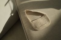 Kaboompics - Beige Crochet Bag on Gray Upholstery with Sunlit Shadows, Minimal Fashion Still Life