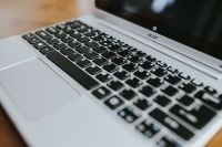 Kaboompics - Macro Detail of Silver Laptop Keys and Touchpad on a Wooden Table