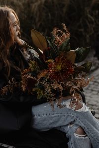 Kaboompics - Woman Holding a Large Autumn Bouquet While Sitting Outdoors
