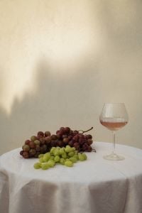 Kaboompics - Red and Green Grapes with Wine Glass on White Tablecloth