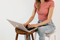 Kaboompics - Woman Working on a Laptop from a Wooden Stool, Casual Home Office Lifestyle Photo
