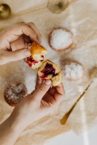 Kaboompics - Overhead Hands Splitting a Cherry-Filled Paczki among Sugar-Dusted Doughnuts