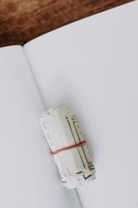 Kaboompics - US Dollar Banknotes Bundled with a Red Band on an Open Notebook, Minimal Finance Flat Lay
