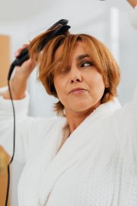 Kaboompics - Close-Up of a Woman Straightening Short Brown Hair with a Flat Iron