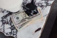 Kaboompics - Dollar Bills with Black Ceramic Sculpture on White Marble