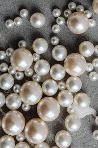 Kaboompics - Large and Small Pearl Beads Scattered on Textured Gray Concrete, Vertical Flat Lay