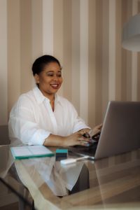 Kaboompics - Black Woman Using Laptop Beside Planner in Home Office