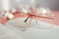 Kaboompics - Close-Up Reading Glasses over Book Pages with Candle Bokeh