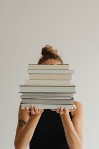 Kaboompics - Close-Up of a Woman Holding a Neutral Stack of Books