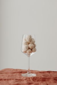 Kaboompics - Coconut Truffles in a Stemmed Glass on Rust Linen, Minimal Food Still Life with Copy Space