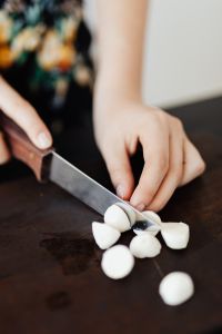 Kaboompics - Close-Up of Hands Chopping Salad Ingredients on a Dark Cutting Board