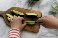 Kaboompics - Halving Fresh Cucumbers on a Wooden Paddle Board with Jar in Background