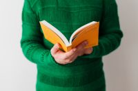 Kaboompics - A man in a green sweater reading a book, white background