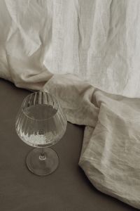Kaboompics - Empty Stemmed Glass on a Dark Table Beneath Draped Linen
